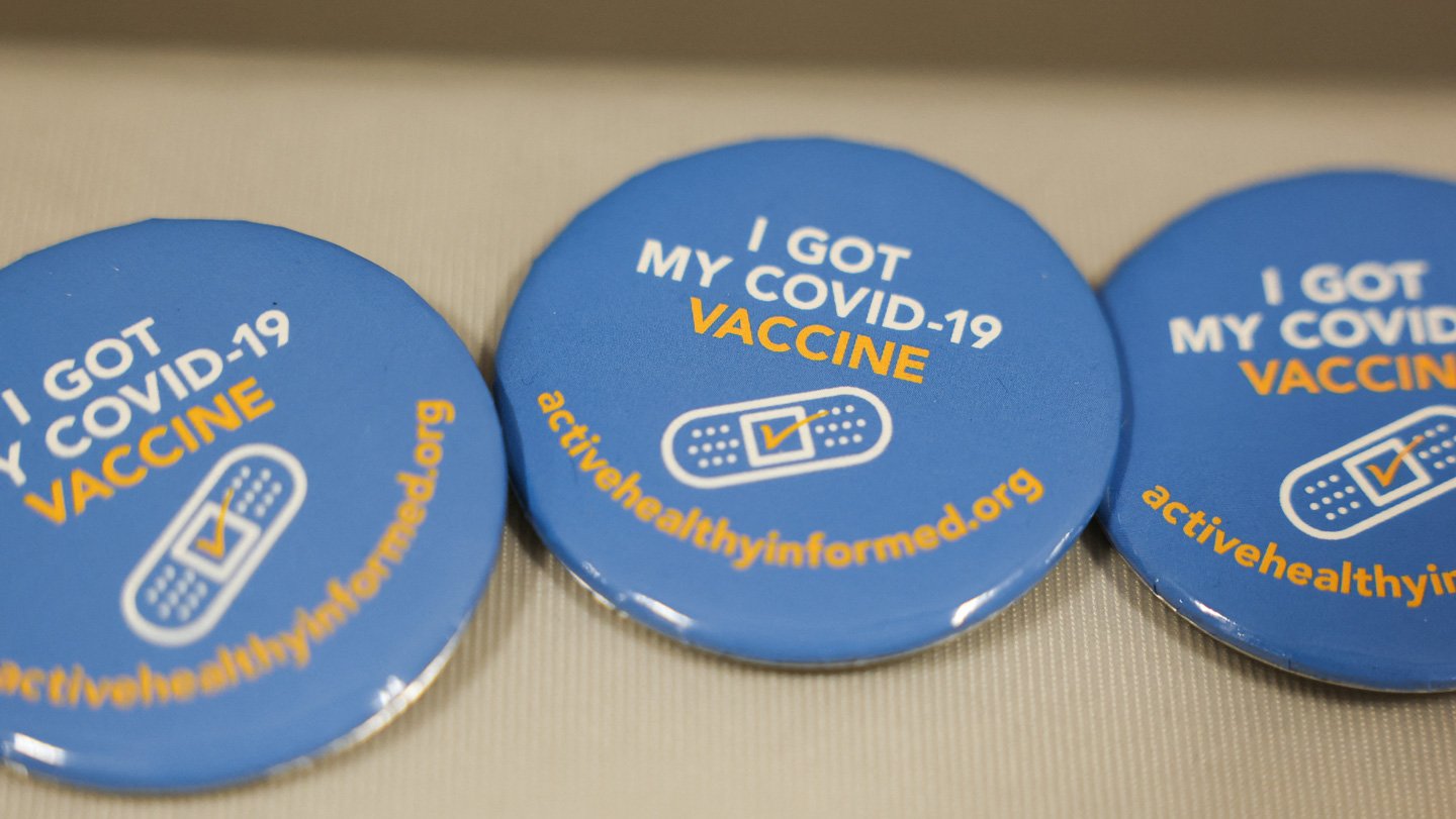 An October 2025 immunization event in a Los Angeles neighborhood had COVID-19 vaccination buttons...