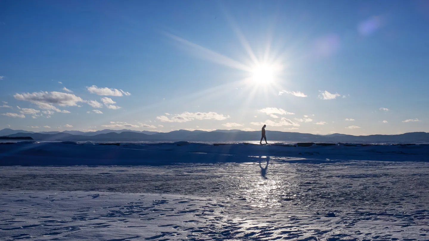 A man walks across frozen Lake Champlain in Burlington, Vt., in February. The lake, which used to...