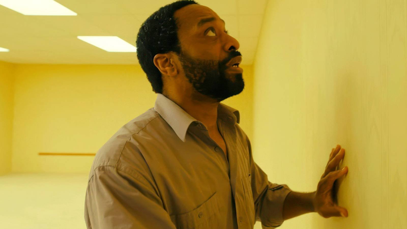 Chiwetel Ejiofor as Clark nervously touching a wall in Backrooms