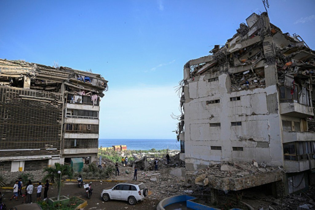 People stand before damaged apartment buildings following an earthquake in Catia La Mar, La Guair...