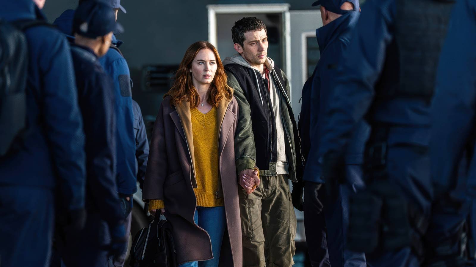 Emily Blunt and Josh O'Connor Standing In Front Of A Group Of Guards In Disclosure Day